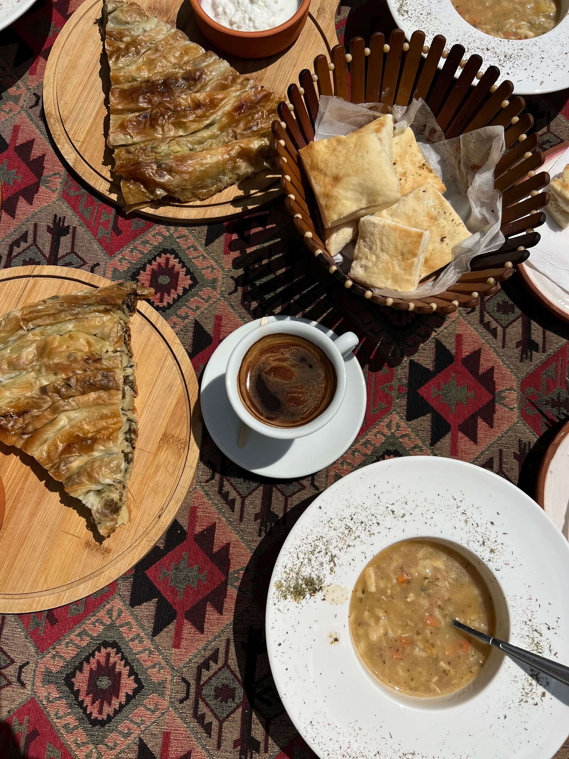 A Bulgarian table set with banitsa and a bowl of hot soup