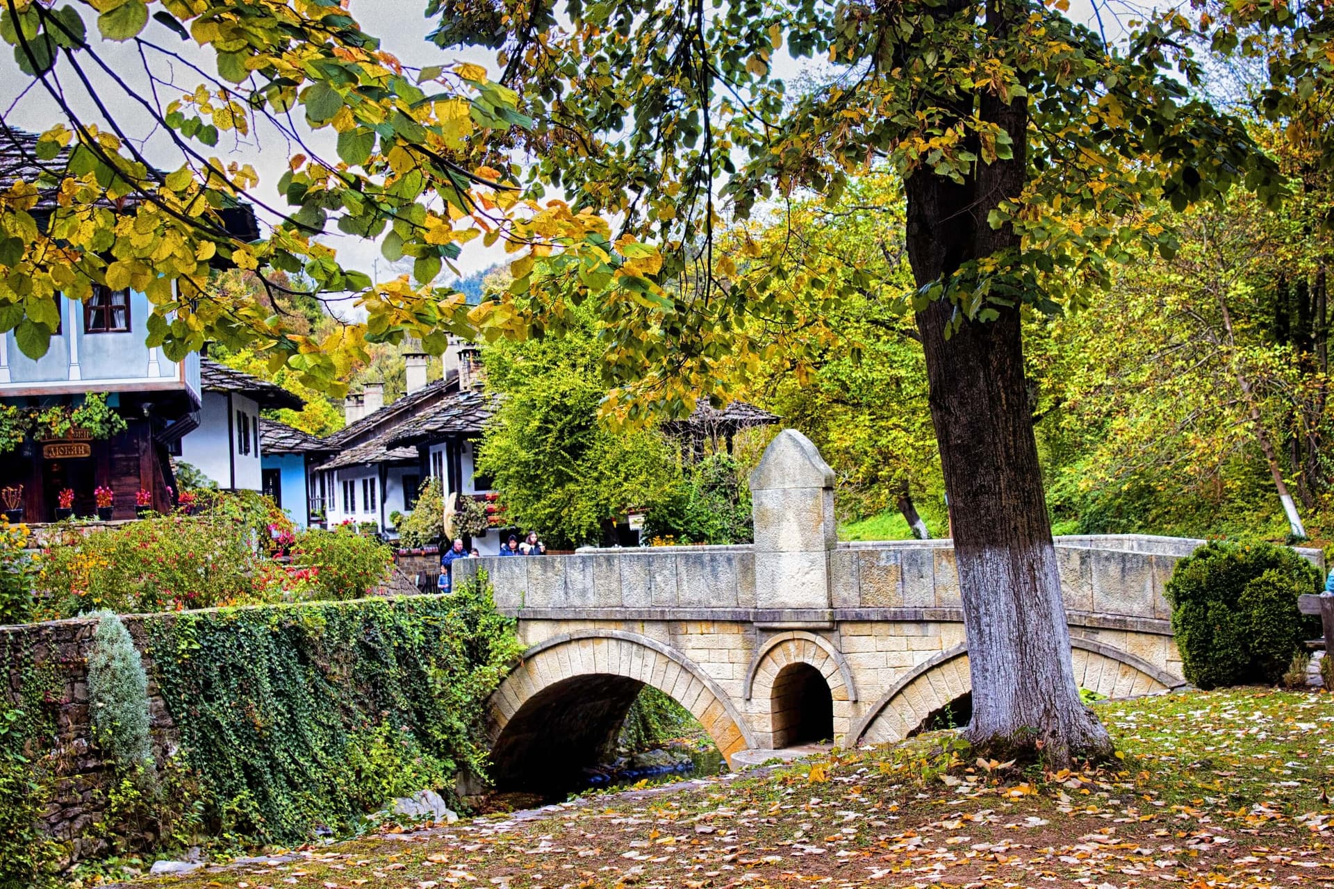 The arched stone bridge over the stream at Etar, with the craft-street houses beyond in autumn