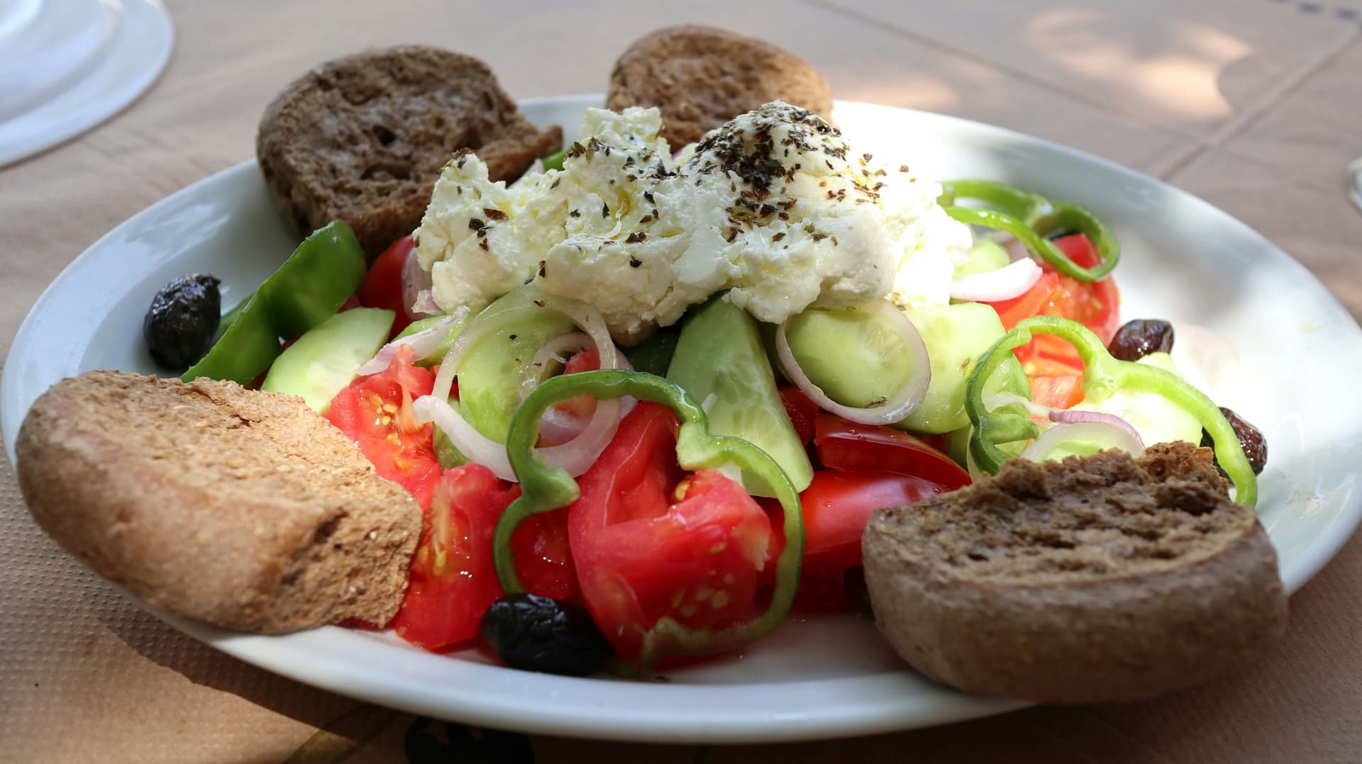 A bowl of Shopska salad topped with grated white sirene cheese