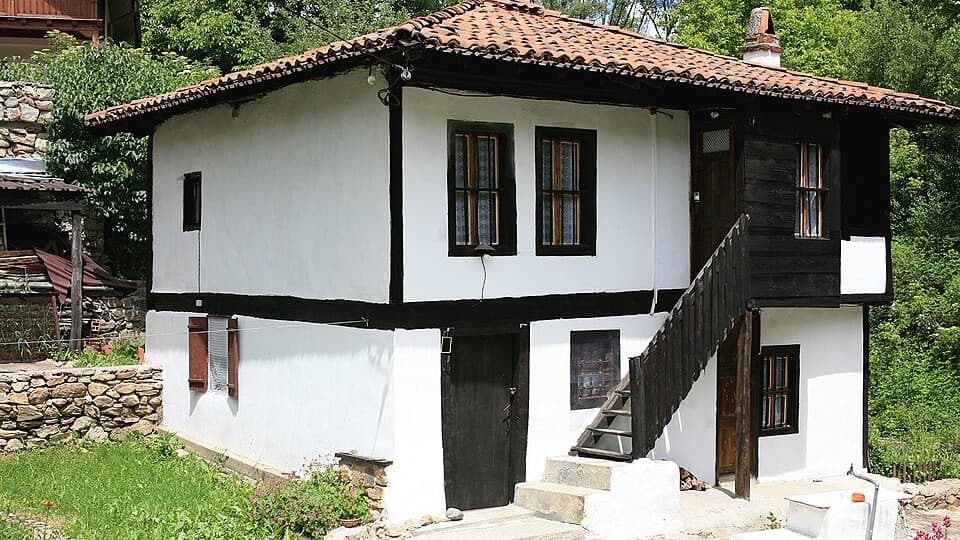 A restored Revival house in Svezhen, whitewashed with dark timber framing and an external wooden staircase