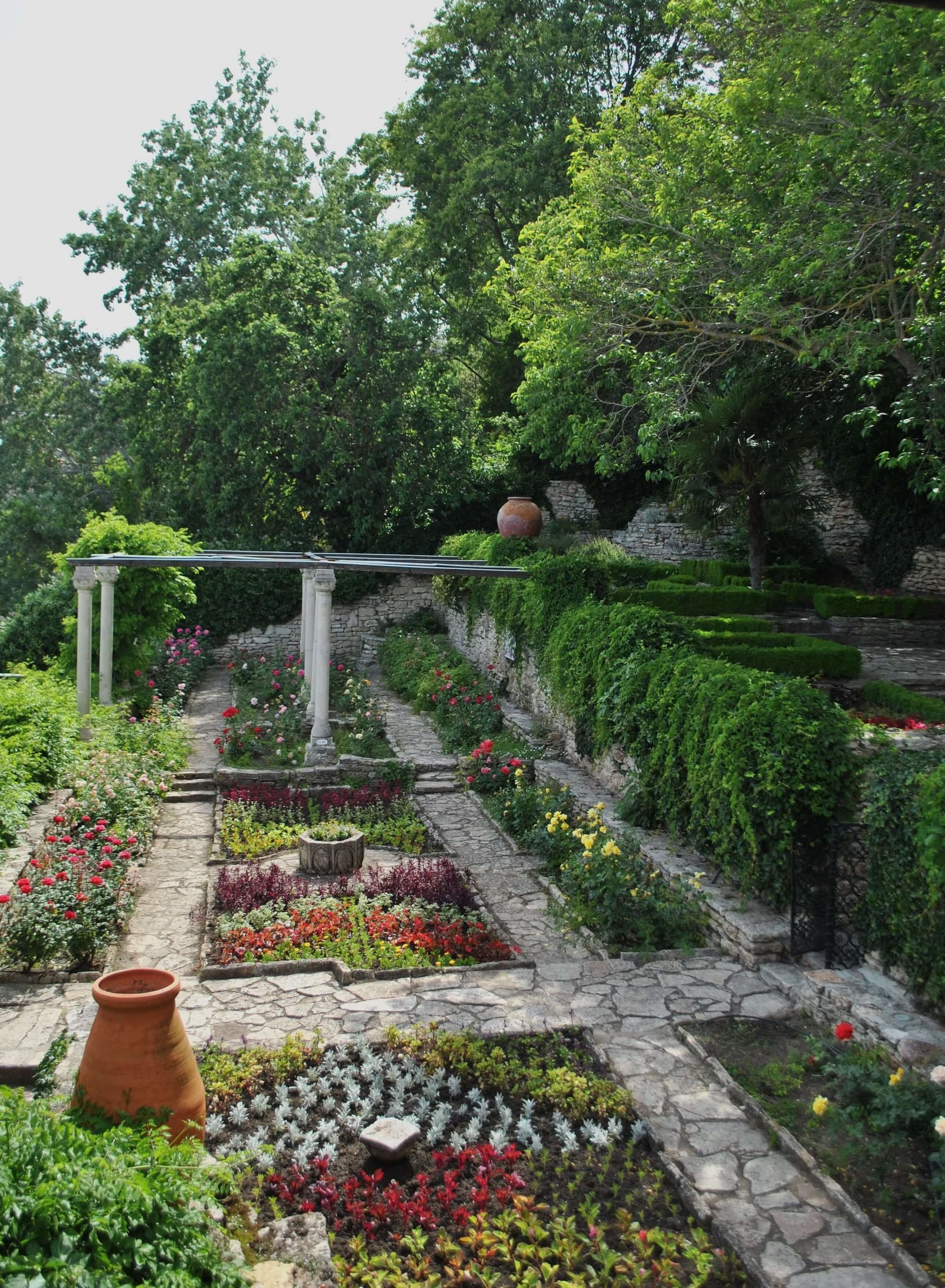 Rose beds, a stone colonnade and clipped hedges stepping down the garden terraces