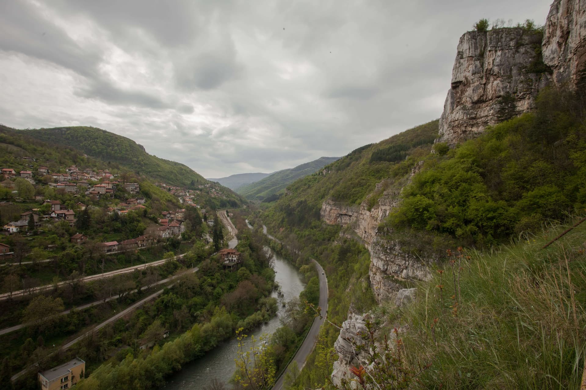 The pale limestone wall of the Lakatnik rocks rising above the Iskar and the railway line