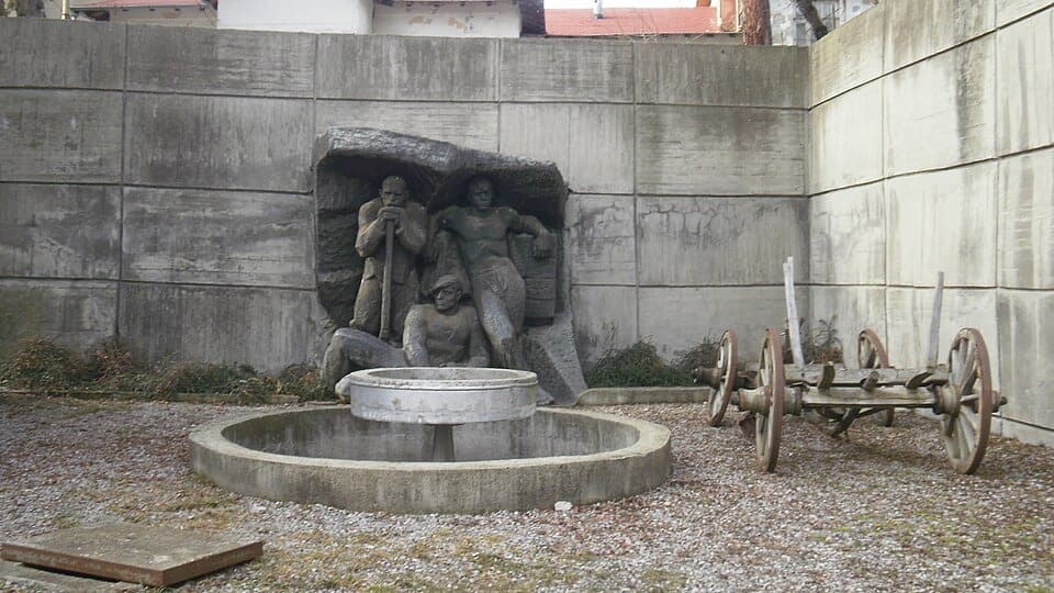The miners' relief and an old wooden-wheeled mine wagon in the courtyard above the Pernik mining museum