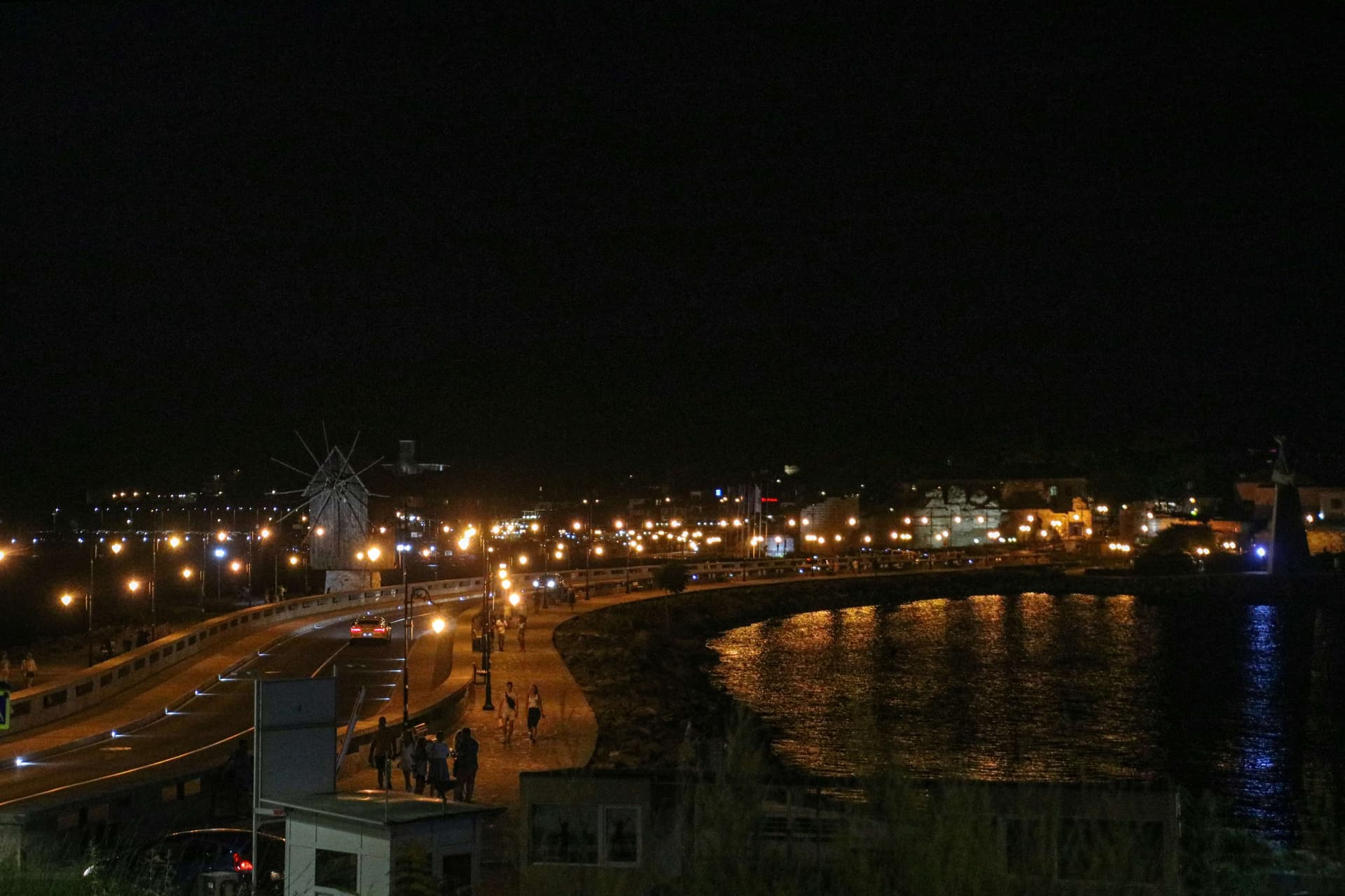 The causeway to Nessebar old town lit at night, with the landmark windmill