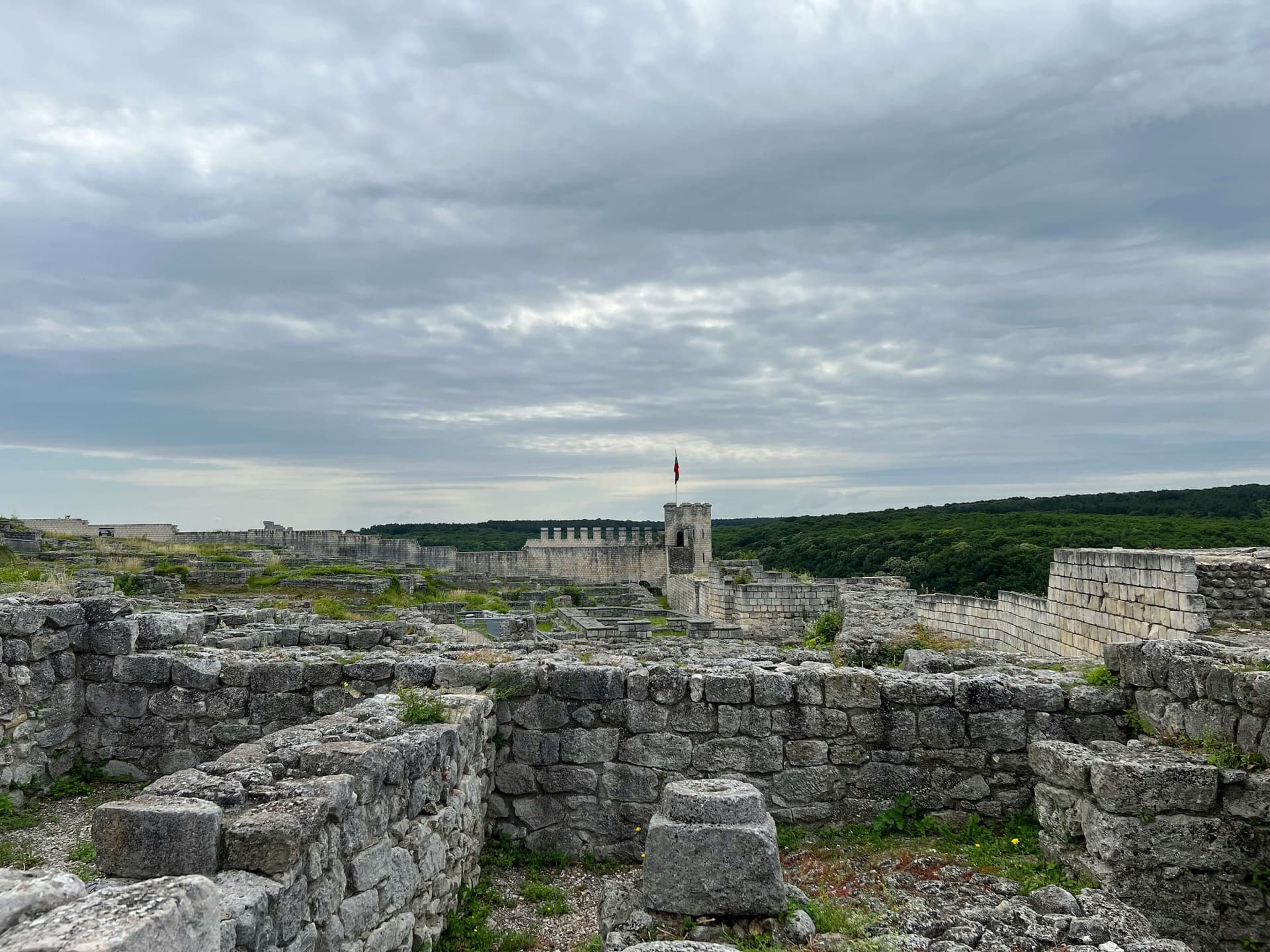 The stone foundations of Shumen fortress, with a restored wall and tower flying the Bulgarian flag